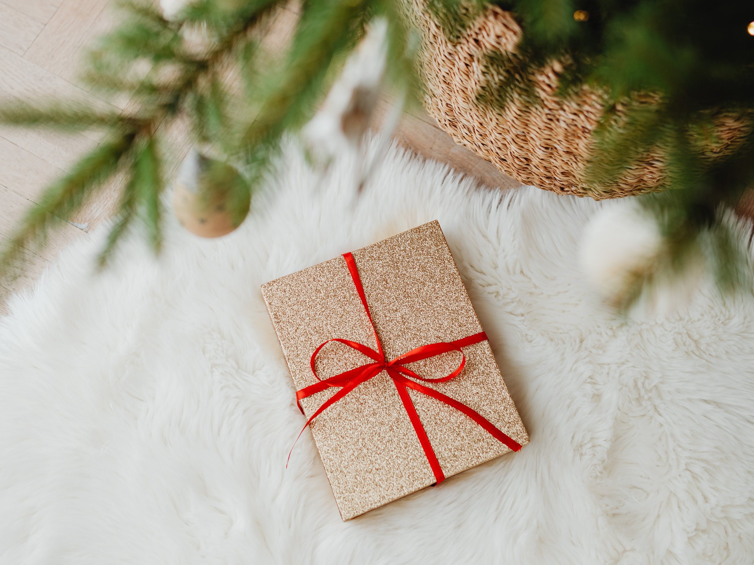 A stylish arrangement of high-quality, clutter-free gifts on a wooden table, representing the categories of functional items, consumables, and experiences, next to a cozy chair.